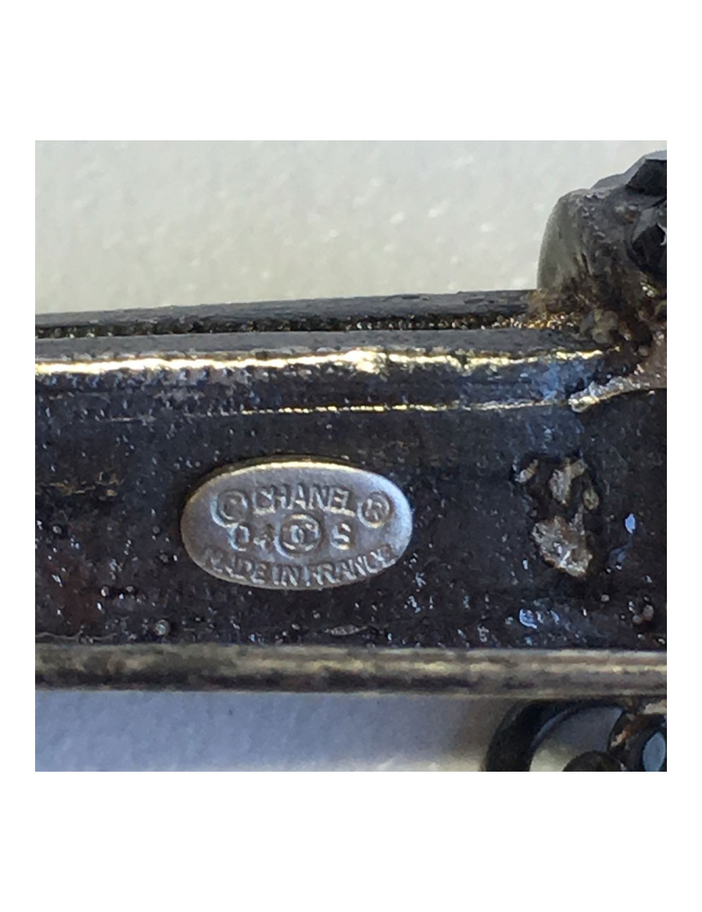 Broche CHANEL en métal ruthenium, strass gris et perle grise